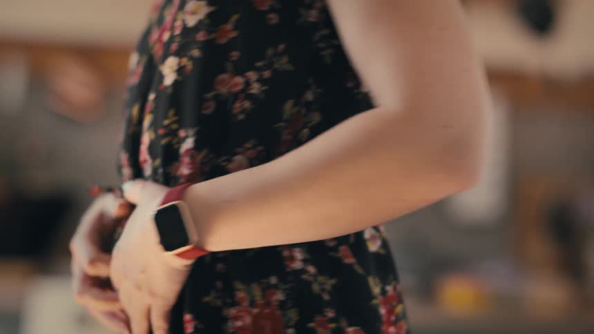 A woman wearing a floral dress spins while modeling in front of a mirror in a warmly lit room