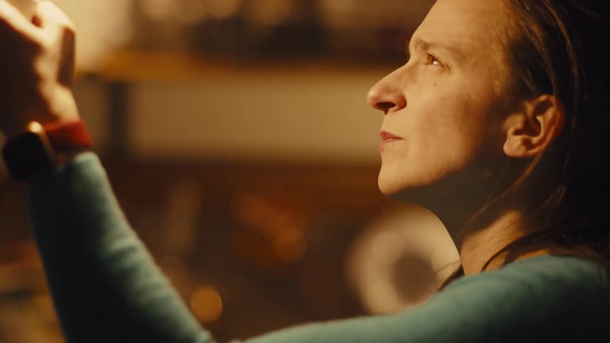 A woman closely examines a glowing light bulb indoors