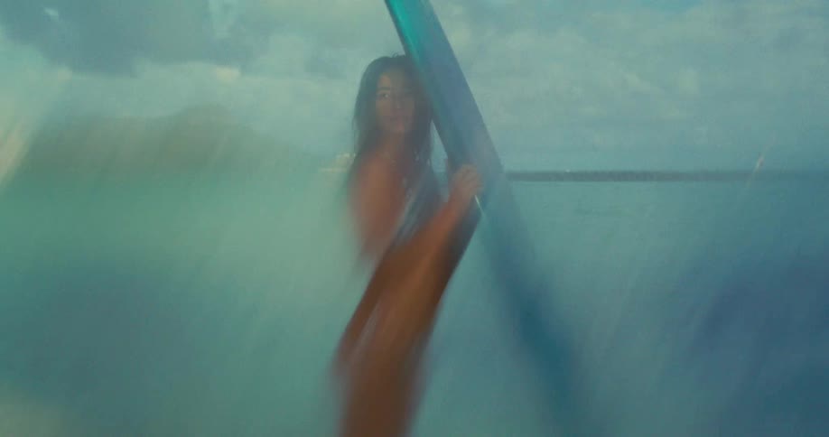 A woman is modeling with a surfboard on the beach