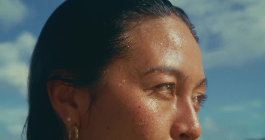 Woman with beads of water on her face on a warm cloudy day