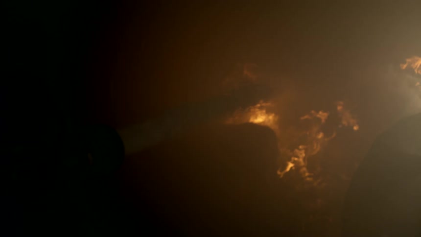 Firefighter turns on the fire hose and directs the water at a blazing fire