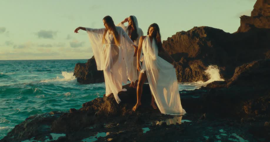 Three women on a rocky shore at the beach posing