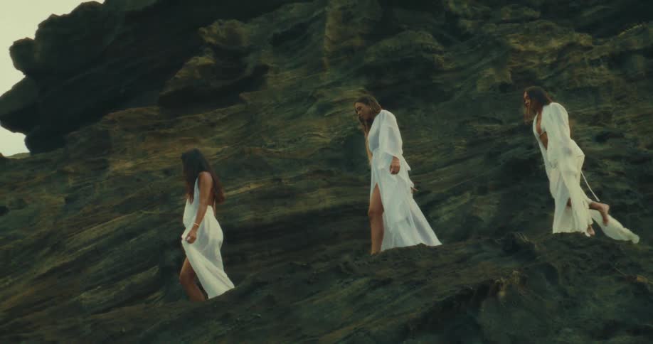 Three women walking on top of a large rock