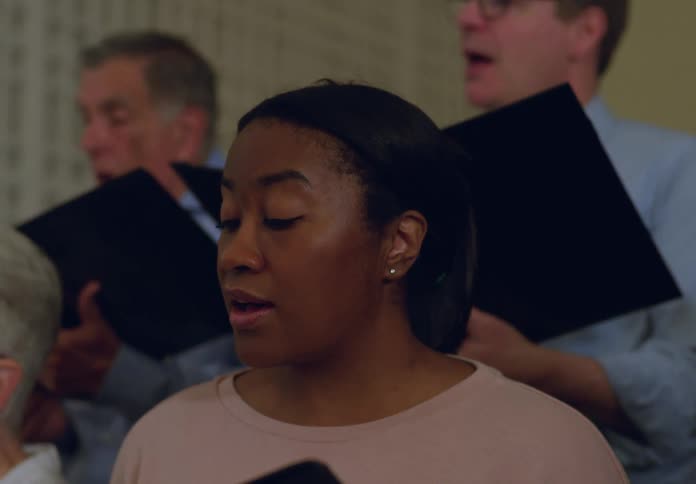 A group of people is singing in a choir indoors