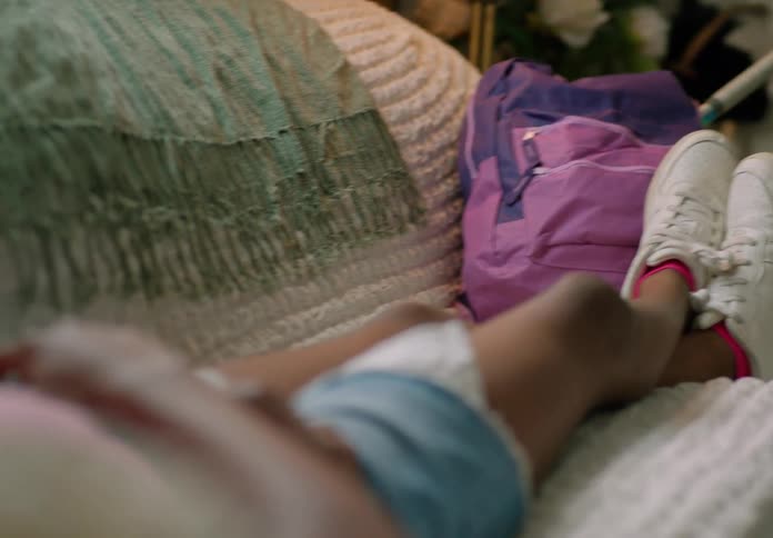 Girl lies on the couch with a backpack near her feet