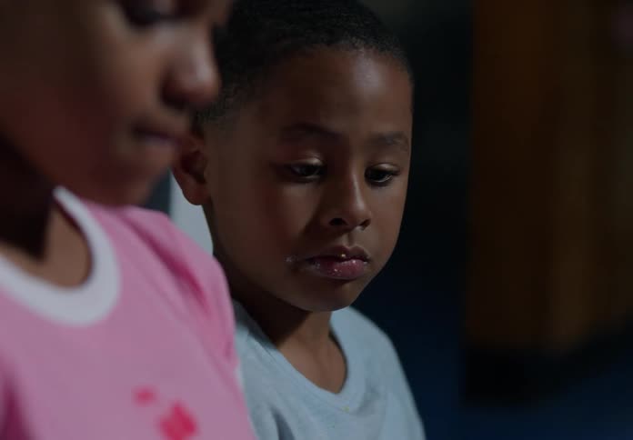 A young boy looks at a girl beside him sharing a quiet emotional moment
