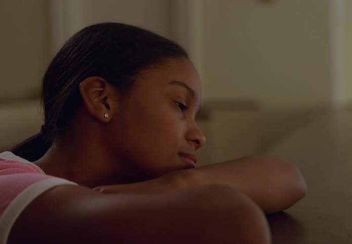 A girl leaning on a counter with her arms crossed observing something