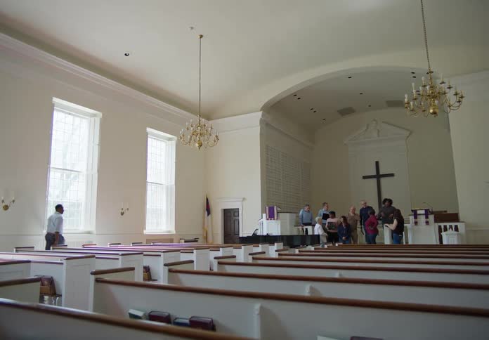 A man arrives at a church where some people are on the altar he walks toward them and claps his hands