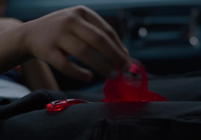 A boy rests in a car seat playing with a red stretchy toy while looking bored and contemplative