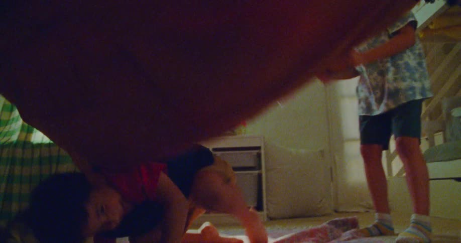 Children play with a blanket in the bedroom