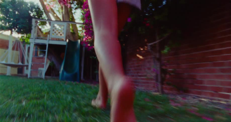 A child runs through the grass barefoot