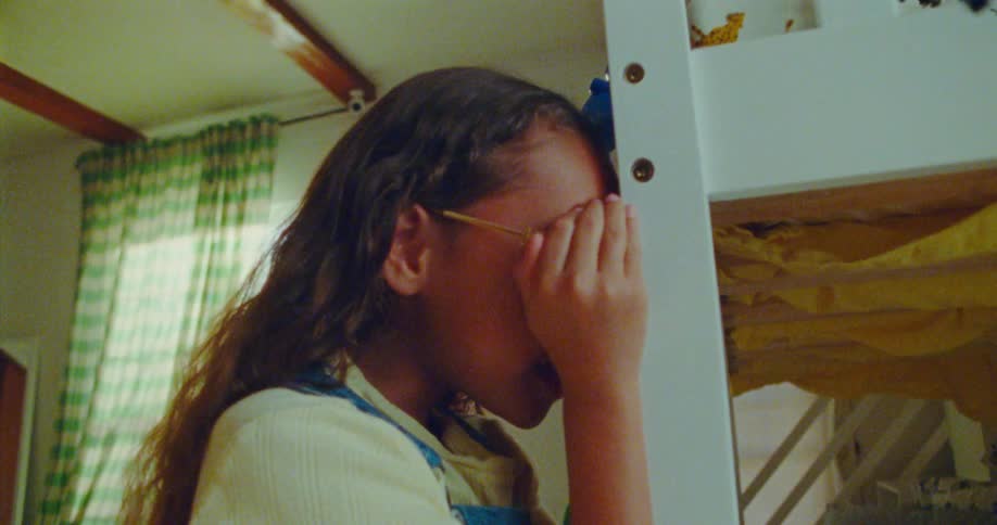 A little girl is counting with her hands covering her eyes and then runs off