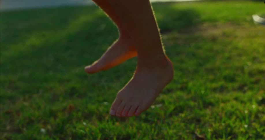 Closeup of a person barefoot midjump on a grassy field outdoors