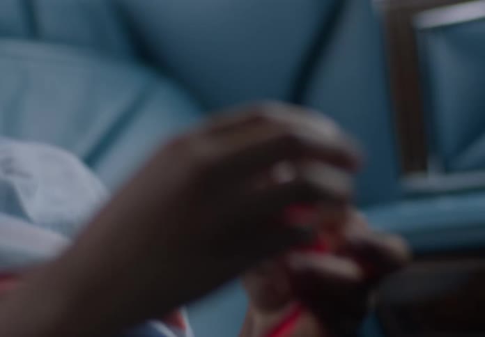 A boy sits in the backseat of a moving car playing with a red stretchy toy