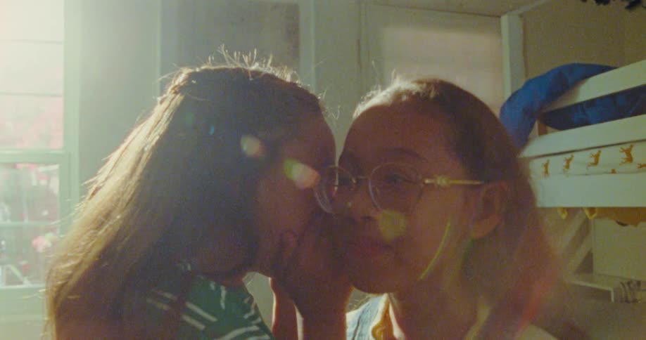 Two little girls whisper secrets and giggle joyfully in a moment of playful fun
