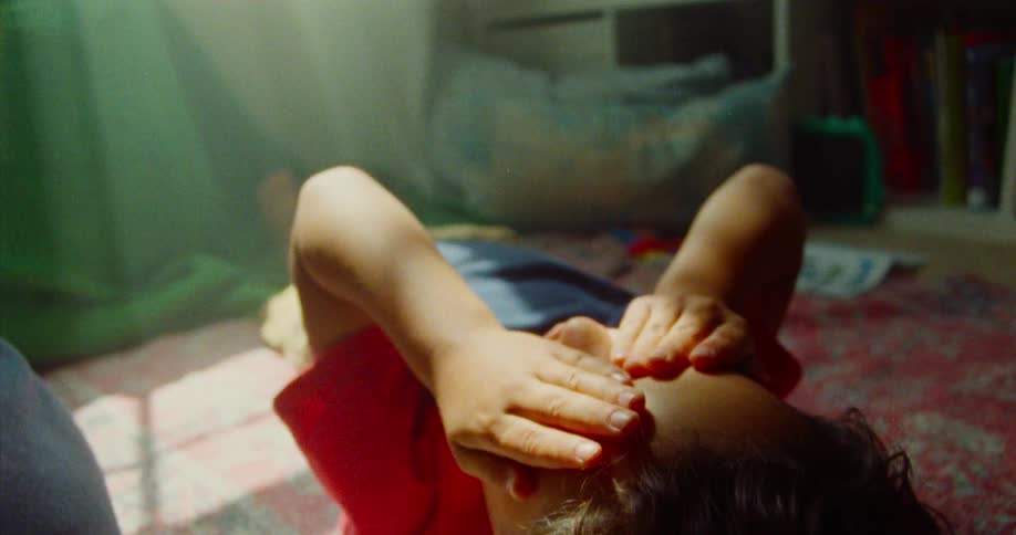 Boy lying on bedroom carpet with hands on face
