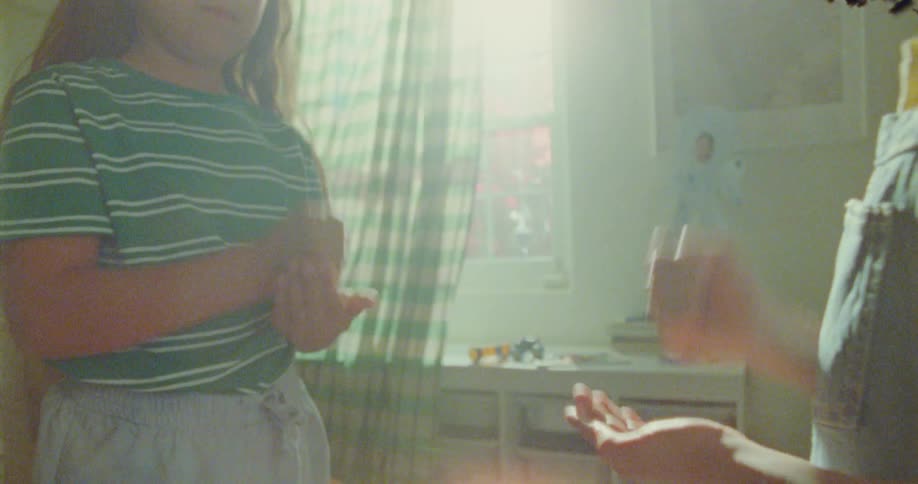 Two kids play rockpaperscissors in a room at midday