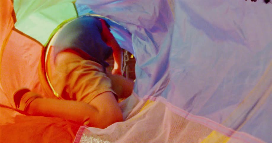 A child with short dark hair crawls through a colorful play tunnel