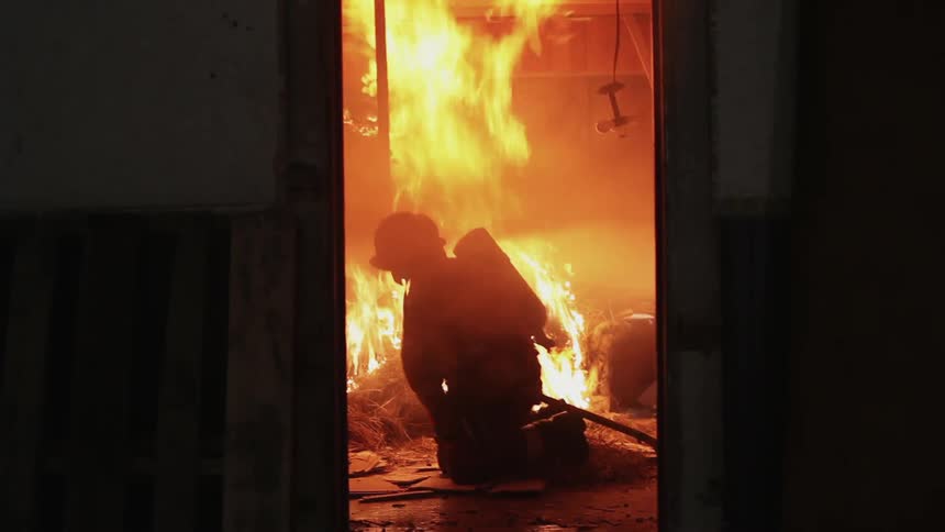 Firefighter sitting and adjusting equipment in burning room