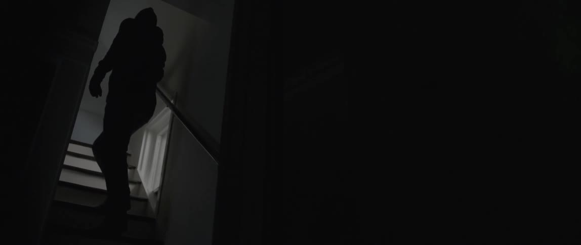 A man sneaks up the stairs of a house