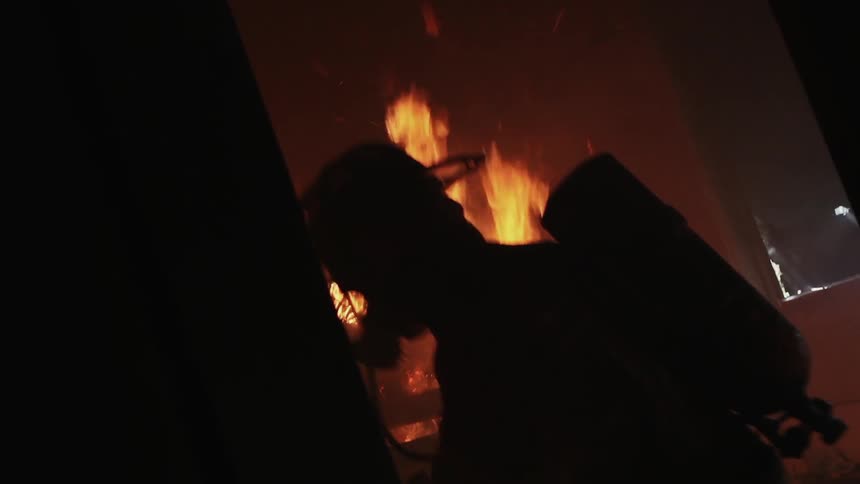 A firefighter is standing near a burning fire