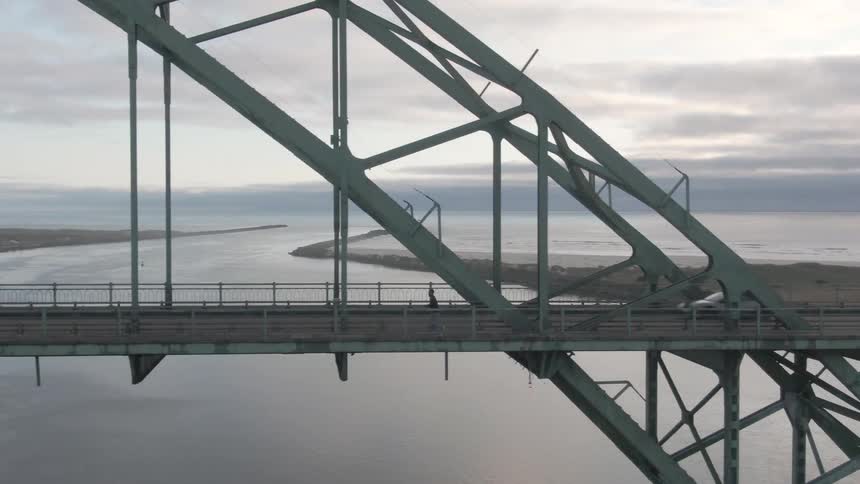 Person running on a suspension bridge with vehicles passing by