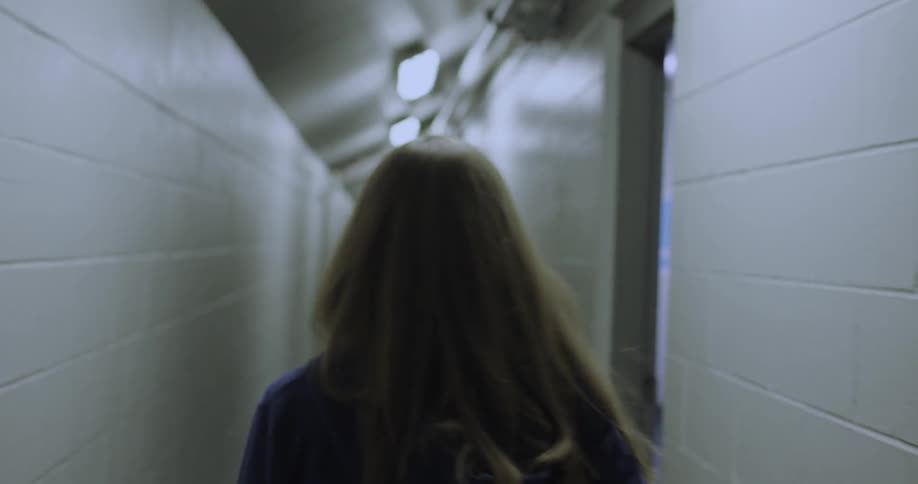A woman walks down a narrow hall into a room