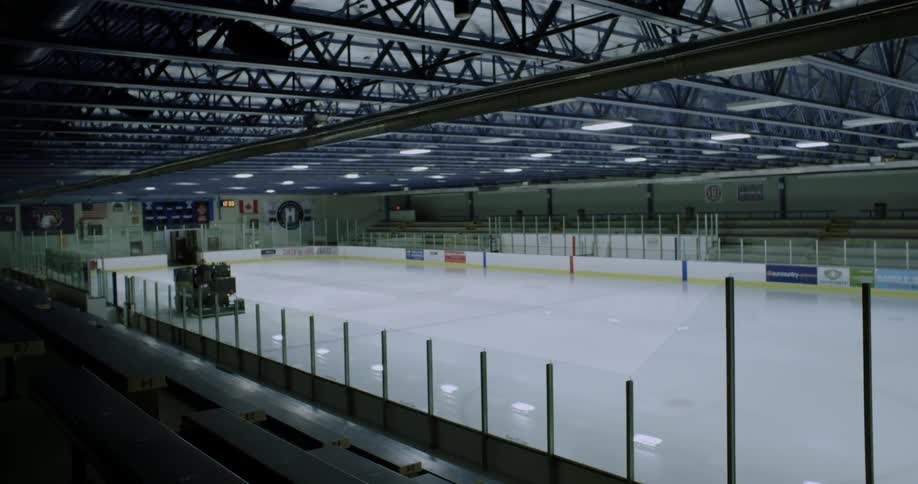 A zamboni drives on an indoor ice skating rink