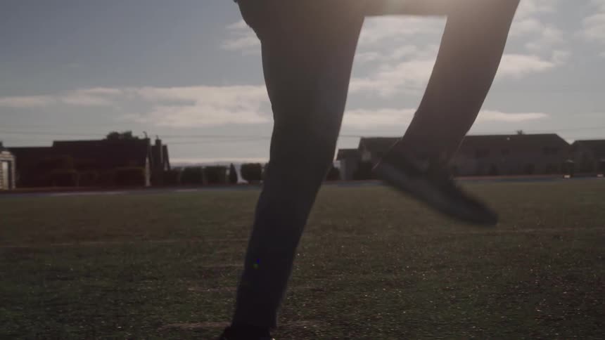Close up of a persons legs warming up on a grass field