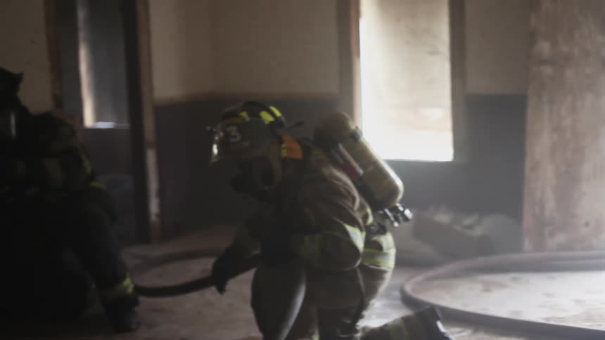 Firefighters in full gear stand ready in a room