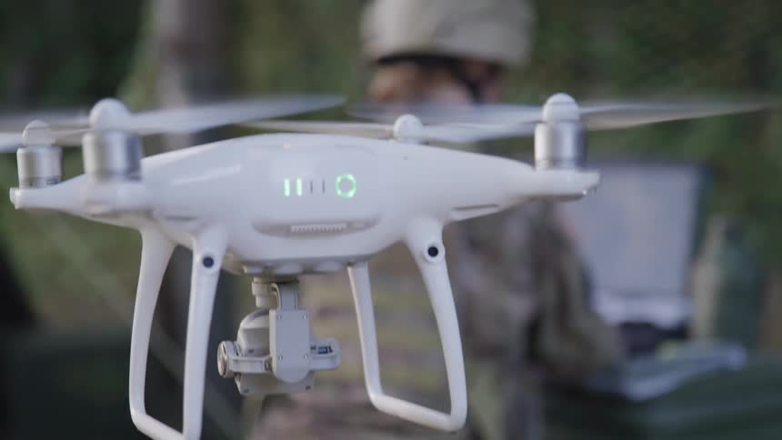 A soldier controls a drone from a laptop