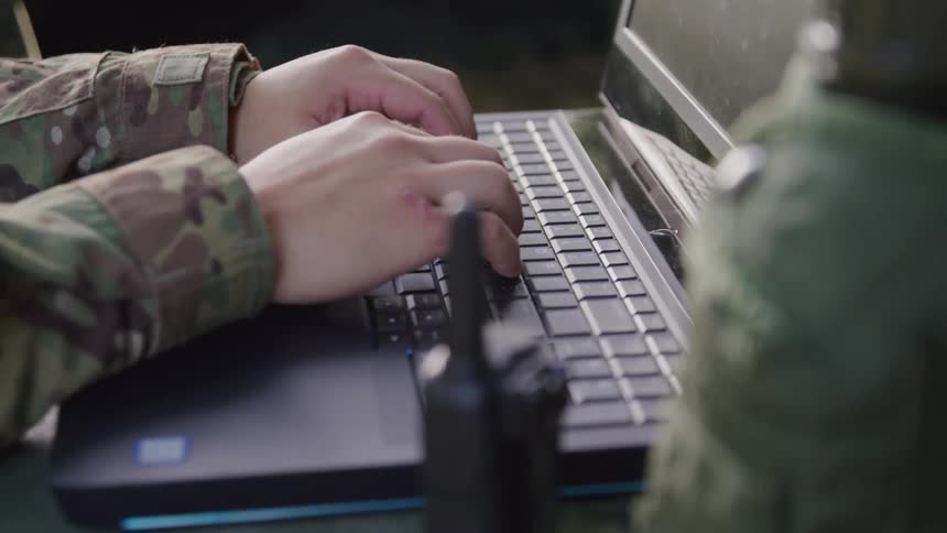 A soldier is typing on the laptop