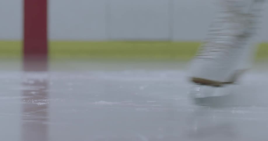A figure skaters white skates come to a stop on the ice