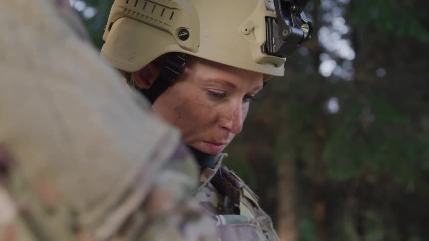Female soldier concentrated next to another soldier