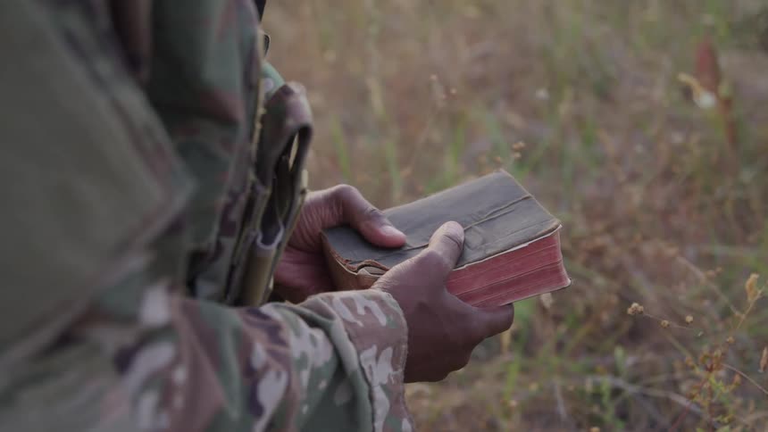 A soldier is holding a book in his hands