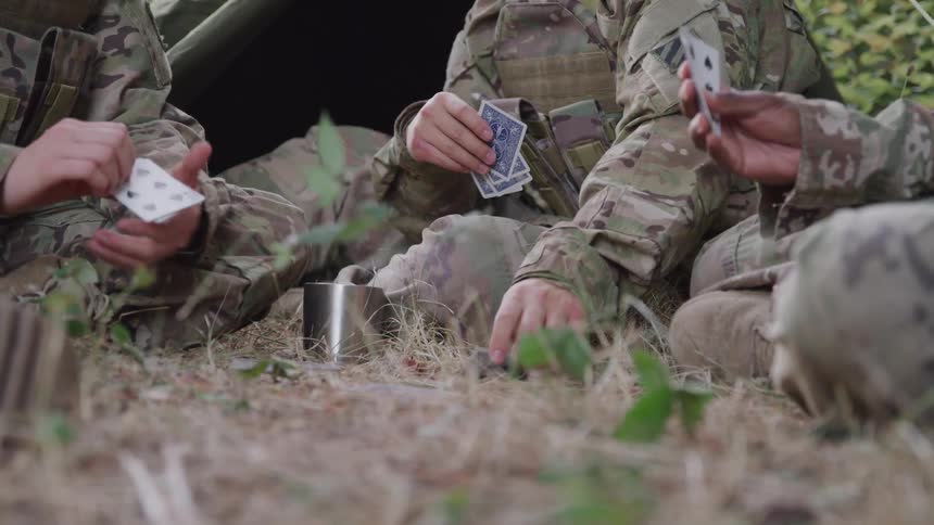 Three soldiers sitting on the grass playing cards