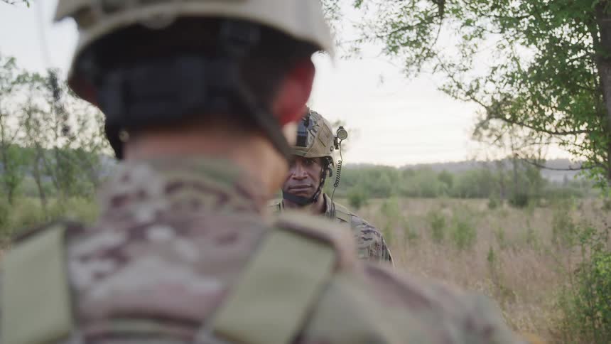 Two soldiers salute each other in a field