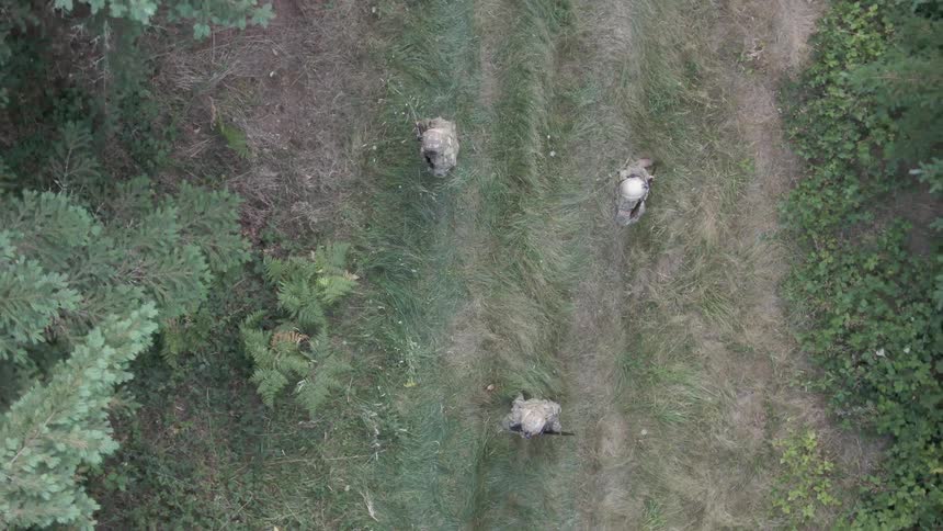 Overhead view of three armed soldiers on a forest trail