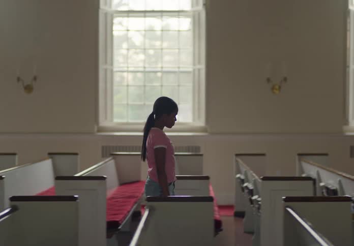 Girl gets up from a church pew and walks towards the altar with a piano