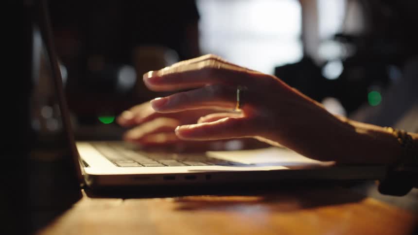 Pair of hands typing on a laptop on top of a table