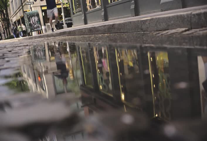 City street reflection of buildings and lights in a puddle on cobblestones