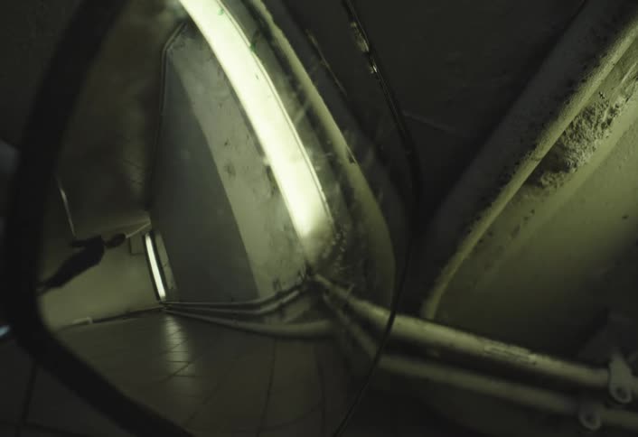 A person is seen running reflected in a convex mirror in a dimly lit hallway