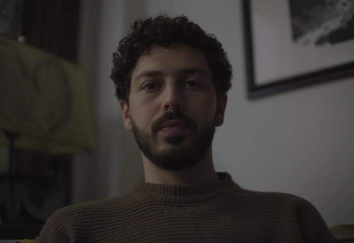 Portrait of a bearded man sitting indoors and wearing a brown sweater