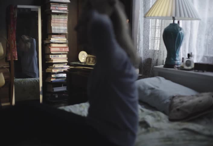 A woman stretches joyfully in bed after waking up on a peaceful day