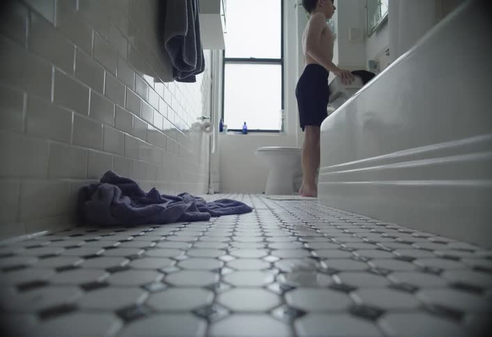 A boy walks to the sink in the bathroom