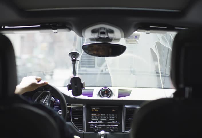 Rear view mirror shows a driver shaking his head slightly when coffee spills down his windshield