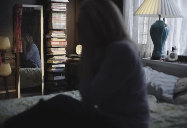 A woman wakes up and sits up quickly in bed appearing to rush into her day