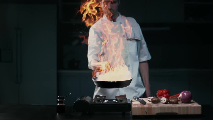 A chef is holding a pan on fire