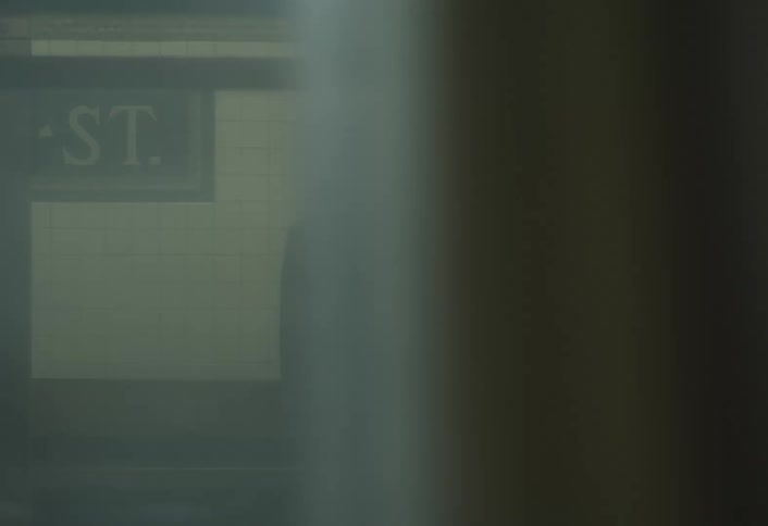 Woman in blazer standing in subway station with trains passing by