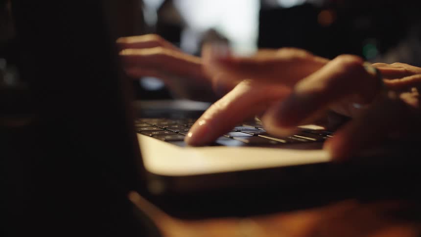 Closeup of female hands typing rapidly on a laptop keyboard
